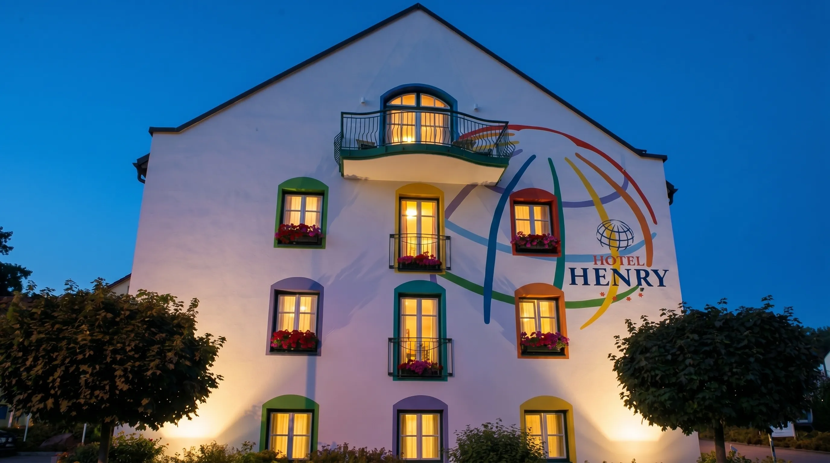 Das Hotel Henry mit seinem bunten Weltkugel-Wandbild zur blauen Stunde, warm erleuchtete Fenster (Originalaufnahme, digital aufbereitet, KI-erweitert und in Abendstimmung versetzt).